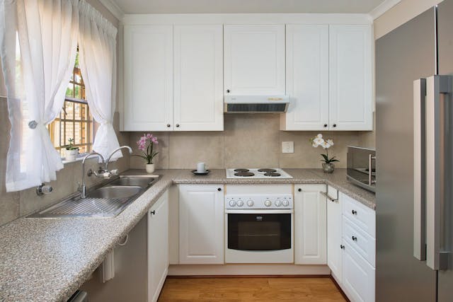 Galley kitchen layout with white cabinets, compact design, and natural light in a Michigan home