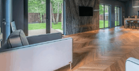 Modern living room with large glass doors natural light and herringbone wood flooring