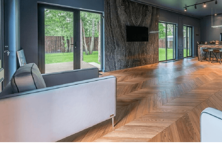Modern living room with large glass doors natural light and herringbone wood flooring