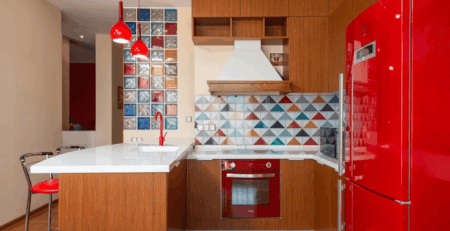 Small kitchen renovation with red refrigerator, wood cabinets, and colorful tile backsplash in a modern Michigan home