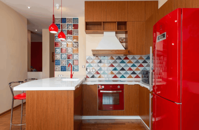 Small kitchen renovation with red refrigerator, wood cabinets, and colorful tile backsplash in a modern Michigan home