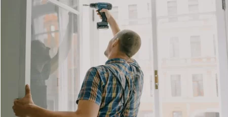 Contractor installing window using power drill during home remodeling project