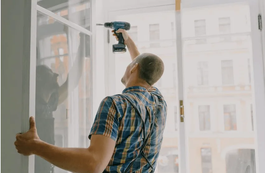 Contractor installing window using power drill during home remodeling project