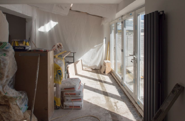 Home renovation in progress with drywall work, construction materials, and large sliding glass doors bringing natural light into a Michigan home